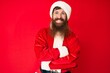 © Krakenimages.com - Handsome young red head man with long beard wearing santa claus costume happy face smiling with crossed arms looking at the camera. positive person.