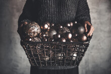 Wire Basket Full Of Christmas Or New Year Tree Golden Vintage Decoration Toys In Hands Of Lady In A Gray Warm Sweater