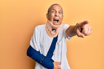 Sticker - Handsome mature senior man wearing cervical collar and arm on sling pointing displeased and frustrated to the camera, angry and furious with you