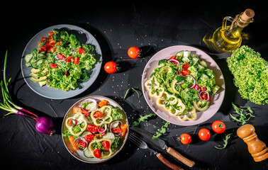 Wall Mural - Healthy vegetable salad of fresh tomato, green leaves mix and vegetables. Top view on dark bacground. Diet menu