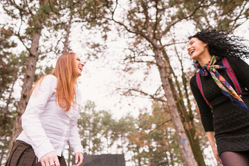 Wall Mural - two girls with long hair having fun in the park, autumn outfit.Two pretty stylish women have fun 