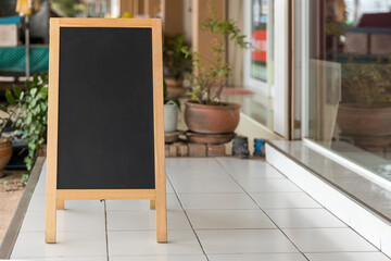 Wall Mural - Wooden rustic blackboard in front of restaurant entrance. Mock up Menu Blank Blackboard sign stand Shop Cafe Restaurant. Street Magnetic Sidewalk Chalkboard.