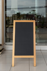 Wall Mural - Wooden rustic blackboard in front of restaurant entrance. Mock up Menu Blank Blackboard sign stand Shop Cafe Restaurant. Street Magnetic Sidewalk Chalkboard.