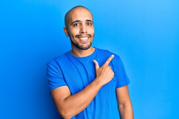 Canvas Print - Hispanic adult man wearing casual blue t shirt smiling cheerful pointing with hand and finger up to the side