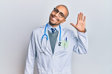 Canvas Print - Hispanic adult man wearing doctor uniform and stethoscope waiving saying hello happy and smiling, friendly welcome gesture