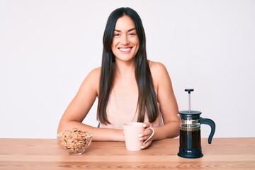 Sticker - Young caucasian woman sitting at the table drinking coffee looking positive and happy standing and smiling with a confident smile showing teeth