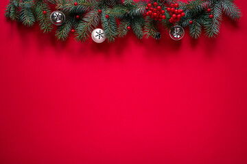 Wall Mural - Christmas red background with fir branches, bells and red decorative berries, space for text, top view