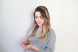 © Hazal - Young woman over isolated gray background sending a message with the mobile