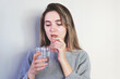 © Hazal - Young woman taking pill on light background, closeup