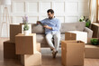 © fizkes - Young Caucasian man sit on couch relocate to new home relax using modern tablet gadget. Millennial male renter rest on moving day look at laptop screen browse surf wireless internet on pad device.