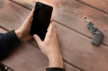 person using mobile phone,  key on the wooden table