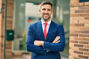 Wall Mural - Young caucasian businessman with crossed arms smiling happy at the city.