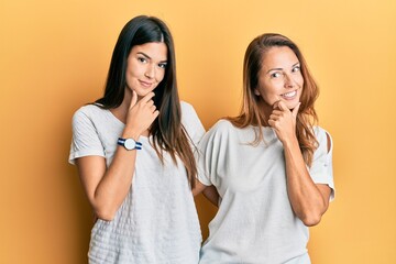 Canvas Print - Hispanic family of mother and daughter wearing casual white tshirt looking confident at the camera smiling with crossed arms and hand raised on chin. thinking positive.