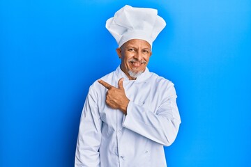 Poster - Middle age grey-haired man wearing professional cook uniform and hat cheerful with a smile of face pointing with hand and finger up to the side with happy and natural expression on face