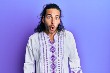 Poster - Young handsome man with long hair wearing bohemian and hippie shirt afraid and shocked with surprise expression, fear and excited face.