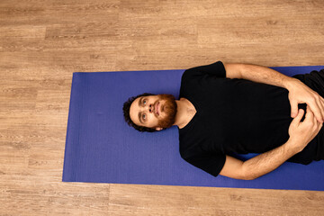 Wall Mural - Young man lying down in a yoga mat.