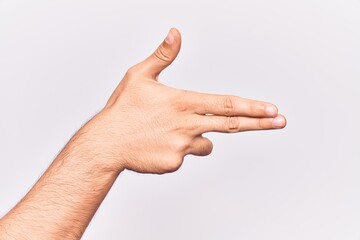 Wall Mural - Close up of hand of young caucasian man over isolated background gesturing fire gun weapon with fingers, aiming shoot symbol