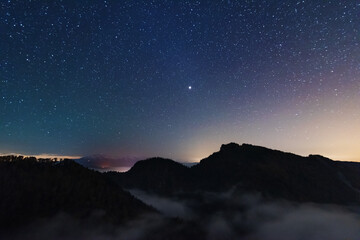 Wall Mural - A beautiful starry night in the mountains on top with beautiful scenery and fog.	