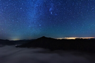 Wall Mural - A beautiful starry night in the mountains on top with beautiful scenery and fog.	