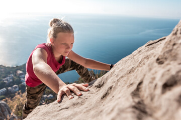 Purposeful young girl climbs to top of mountain. Fingers clinging to rock. Strong female hands during mountain climbing
