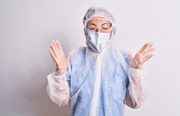 Sticker - Middle age nurse woman wearing protection coronavirus equipment over white background celebrating mad and crazy for success with arms raised and closed eyes screaming excited. Winner concept