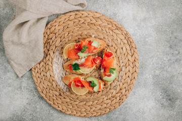 Wall Mural - Smoked salmon sandwich with cream cheese, lemon, avoado and tomato on gray background.