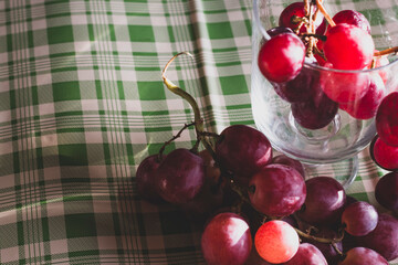 Red grapes, large bunch of fruits, fresh and tasty simple food with brights red and violet colors on a green background in an amazing composition.