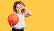 © Krakenimages.com - Beautiful kid girl with curly hair holding basketball ball smiling happy doing ok sign with hand on eye looking through fingers