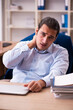 © Elnur - Young male employee suffering from osteochondrosis at workplace