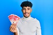 © Krakenimages.com - Young arab handsome man holding 20 israel shekels banknotes looking positive and happy standing and smiling with a confident smile showing teeth