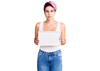 Sticker - Young beautiful woman with pink hair holding empty white chalkboard thinking attitude and sober expression looking self confident