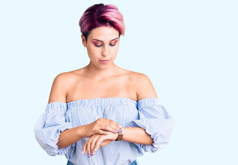 Canvas Print - Young beautiful woman with pink hair wearing casual clothes checking the time on wrist watch, relaxed and confident