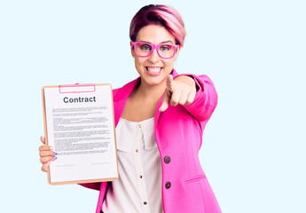 Sticker - Young beautiful woman with pink hair holding clipboard with contract document pointing to you and the camera with fingers, smiling positive and cheerful