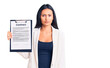 © Krakenimages.com - Young beautiful latin girl holding clipboard with contract document thinking attitude and sober expression looking self confident