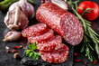 © bukhta79 - Traditional smoked salami sausage with spices.Salami sausage slices on a black chopping Board. Dark background.