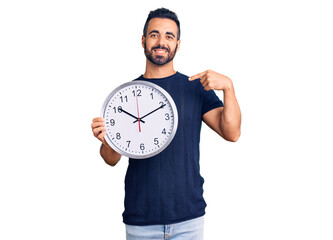 Canvas Print - Young hispanic man holding big clock pointing finger to one self smiling happy and proud