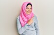 © Krakenimages.com - Young caucasian woman wearing traditional islamic hijab scarf cheerful with a smile of face pointing with hand and finger up to the side with happy and natural expression on face