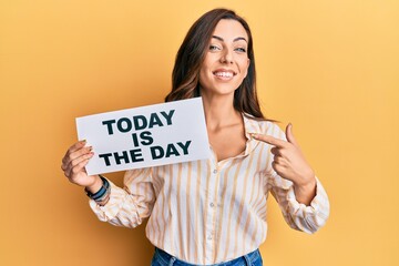 Young brunette woman holding today is the day smiling happy pointing with hand and finger