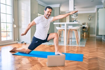 Sticker - Middle age man with beard training and stretching doing exercise at home looking at yoga video on computer