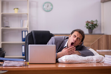 Young male employee sleeping at workplace