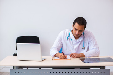 Young male doctor taking notes in the clinic