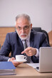 © Elnur - Old male employee drinking coffee during break