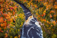 Incredible Aerial Photograph Of The Upper Waterfall Cascade At Tahquamenon Falls With Beautiful Autumn Foliage On The Trees With Green, Yellow, Red And Orange Leaves Surrounding The River.
