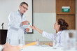 © DragonImages - Experienced scientist giving vial with new vaccine to female colleague at meeting in university