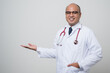 © Chanakon - Doctor in white coat, stethoscope pointing right hand to beside look into camera with smile isolated on white background.
