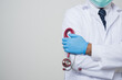 © Chanakon - Asian bald Doctor in white coat, blue glove wearing face mask cross his arm with stethoscope in his hand standing beside camera isolated on white background.