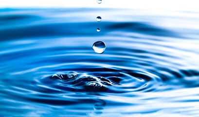 Wall Mural - Dark blue water droplets splash in the water surface  close up. Creating a perfect water wave