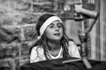 Poster - Young girl wearing Santa Red Hat at home in video call with parents