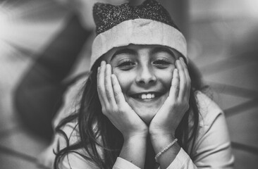 Poster - Young girl lying on the floor at home wearing Santa Red Hat and smiling. Christmas concept