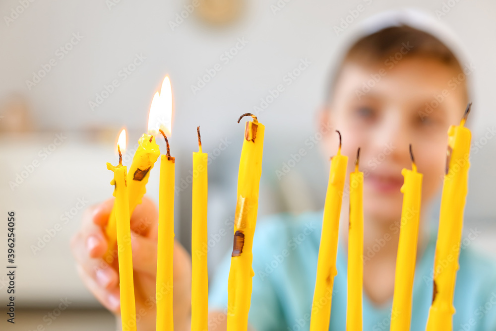 Happy boy lighting candles for celebrating Hannukah at home